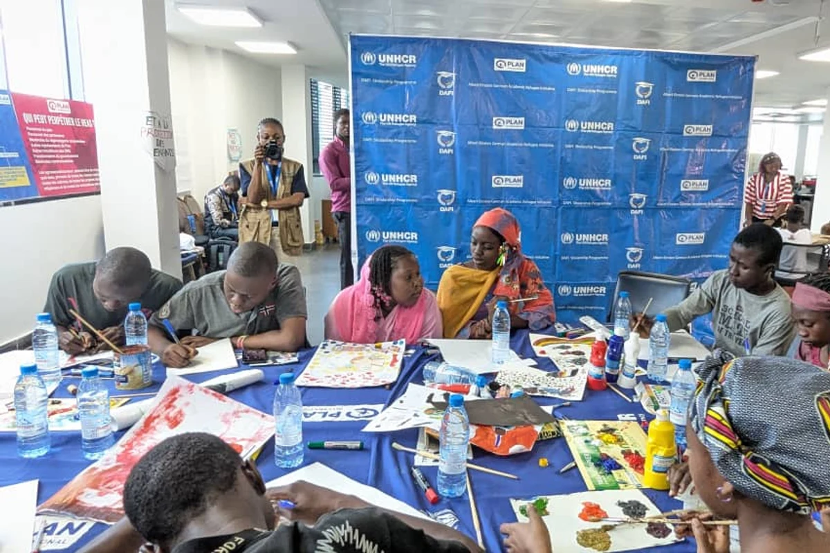 Séance de peinture avec les bannières UNHCR et Plan International en fond